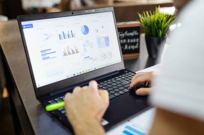 A person analyzing business data and charts on a laptop at Cambrian Labs B.V., focusing on data-driven decision making and analytics.